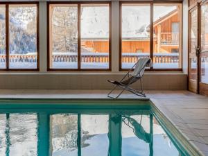 a chair sitting next to a swimming pool in a house at SUNWEB Résidence Les Balcons & Chalets de Bois Méan in Les Orres