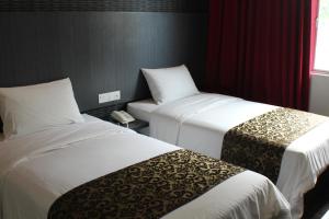 a hotel room with two beds and a window at Hotel Rosmerah in Ayer Keroh