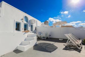 eine Terrasse mit Stühlen und einem Sonnenschirm auf einem Gebäude in der Unterkunft Ilioperato Hotel in Imerovigli