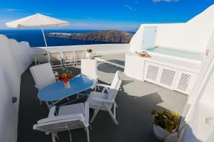 a balcony with a table and chairs on a boat at Ilioperato Hotel in Imerovigli