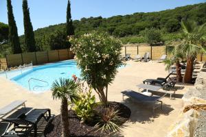 a swimming pool with chairs and palm trees next to it at Ushuaïa Villages Camping Figurotta in Bizanet