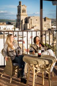 Dos mujeres sentadas en una mesa con una botella de vino en Parador de Arcos de la Frontera, en Arcos de la Frontera