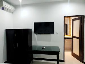 努沙杜瓦的住宿－棕櫚竹酒店，一间设有桌子的房间和墙上的电视