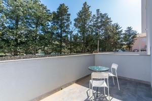 a patio with two chairs and a table on a balcony at Pasko 4 modern furnished ap for 7 in Novalja