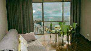 a living room with a couch and a table and chairs at Panorama Sea Tower in Batumi