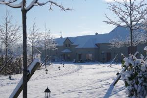 un patio cubierto de nieve con un edificio en el fondo en Le Manoir des Arômes en Brugny-Vaudancourt