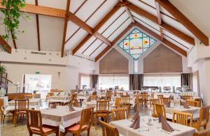 a dining room with tables and chairs and a stained glass window at Orchidea Hotel Lipót in Lipót