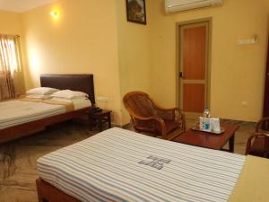 een hotelkamer met 2 bedden en een tafel en stoelen bij Hotel Victoriyah in Thanjāvūr