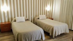 two beds in a hotel room with striped walls at Hostal Anas in Merida