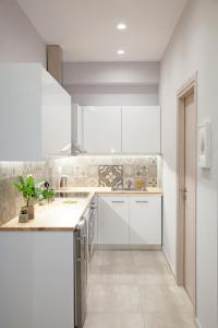 a kitchen with white cabinets and a counter top at Omnia Pagrati Apartments in Athens