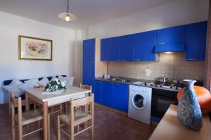 カーラ・リベロットにあるAppartamenti Le Ginestre e Gli Oleandriの青いキャビネットとテーブル付きのキッチン、洗濯機付きのキッチン