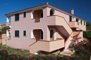 una casa rosa con persianas verdes en una colina en Appartamenti Le Ginestre e Gli Oleandri en Cala Liberotto