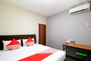 Cette chambre comprend un lit avec des oreillers rouges et un bureau. dans l'établissement Super OYO Capital O 217 A1 Hotel, à Surabaya
