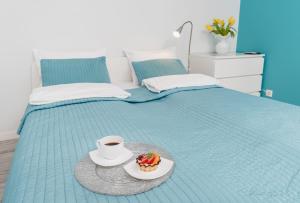 a cup of coffee and a plate of food on a bed at K12 Apartments in Krakow
