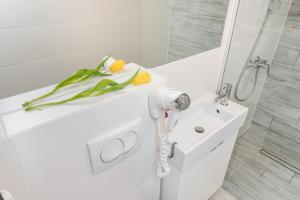 Baño blanco con secador de pelo en un lavabo en K12 Apartments, en Cracovia