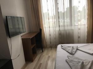 um quarto com uma televisão, uma cama e uma secretária em Hotel Mihaela em Mamaia