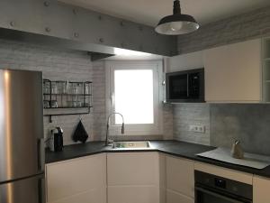 a kitchen with white cabinets and a sink and a window at Serendipia in A Coruña