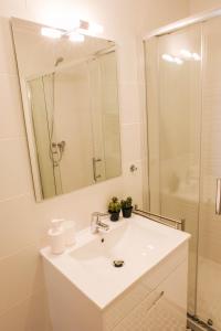 Baño blanco con lavabo y espejo en Cosy Porto, en Oporto