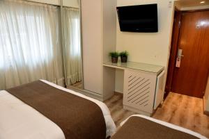 
a hotel room with two beds and a television at Gran Hotel Skorpios in Mar del Plata

