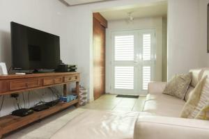 een woonkamer met een witte bank en een flatscreen-tv bij Villa Serena in San Juan