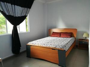 a bedroom with a bed with a wooden headboard and a window at Thilini Tour INN in Ratnapura