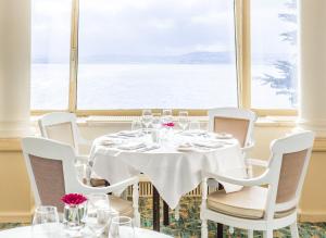 a table with white chairs and a large window at The Imperial Torquay in Torquay