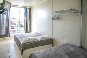 1 dormitorio con 2 camas, TV y ventana en Disponivel Virada - Estúdios e suítes com piscina, ar, wifi e estacionamento 6X no cartão sem juros, en Porto Belo