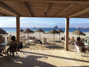 Vila Mira Mar في منديلو: مجموعة من الناس جالسين على شاطئ فيه مظلات