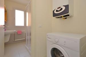 a washing machine in a bathroom with a tv on the wall at Bellarosa in Lignano Sabbiadoro