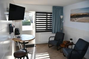 um quarto com uma mesa e cadeiras e uma janela em B&B Waddenzeetexel em Oudeschild