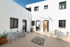 a white house with a patio with a table and chairs at Lindos Olive Suites in Líndos