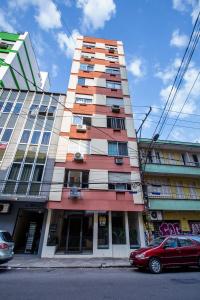a tall building with a red car parked in front of it at Meu lugar na Cidade Baixa in Porto Alegre