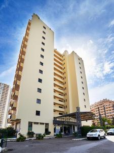 twee hoge gebouwen met een auto geparkeerd op een parkeerplaats bij RR Club Amarilis in Portimão