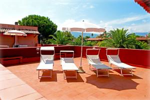 - un ensemble de chaises et d'un parasol sur la terrasse dans l'établissement Portorosa Residence, à Furnari
