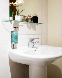 La salle de bains est pourvue d'un lavabo avec une étagère en verre. dans l'établissement The Spires Serviced Apartments Aberdeen, à Aberdeen
