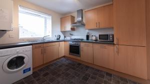 a kitchen with wooden cabinets and a washer and dryer at The Spires Serviced Apartments Aberdeen in Aberdeen
