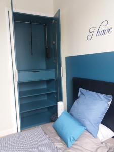 een slaapkamer met een bed met een blauw hoofdeinde bij Coté Cour in Bergues