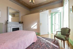 a bedroom with a bed and a chair and a fireplace at Résidence La Villa Léonie in Nice