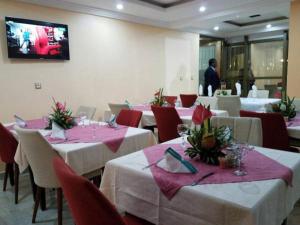 a dining room with white tables and red chairs at Mbayaville Hotel in Douala
