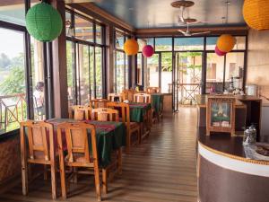 un restaurante con mesas y sillas en una habitación con ventanas en Jungle Wildlife Camp, en Sauraha