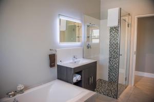 a bathroom with a tub and a sink and a shower at The Whale on Main B&B in Hermanus