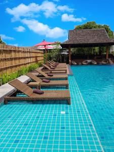 a swimming pool with lounge chairs and an umbrella at PAN KLED VILLA eco hill resort - SHA extra plus in Chiang Rai