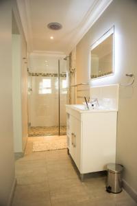 a bathroom with a sink and a shower with a mirror at The Whale on Main B&B in Hermanus