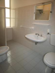 uma casa de banho branca com um lavatório e um WC em Occidente em Lignano Sabbiadoro