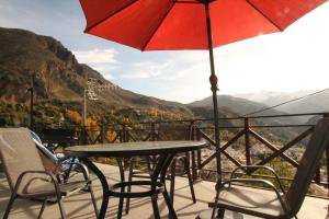 un tavolo e sedie su un balcone con ombrellone di estudio mirador a Güéjar-Sierra