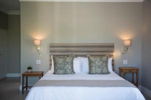 a bedroom with a large white bed with two tables at The Whale on Main B&B in Hermanus