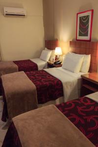 a hotel room with three beds and a lamp at Convair Hotel in Ciudad del Este