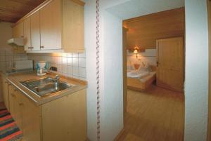 una cucina con lavandino e una camera con letto di Frühstücks- & Apartmenthaus Maislau a Rauris