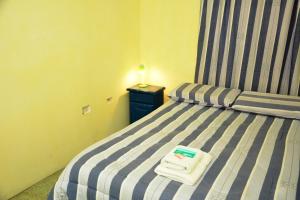 1 dormitorio con 1 cama a rayas y toallas en Hostal Bernardo Salta en Salta