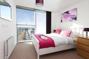 a bedroom with a white bed with pink pillows at 2 Bedroom 2 Bathroom Apartment in Central Milton Keynes with Free Parking and Smart TV - Contractors, Relocation, Business Travellers in Milton Keynes
